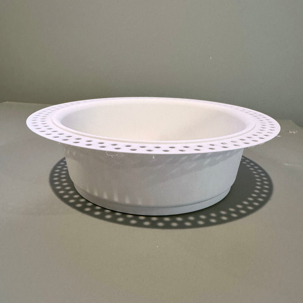Side view of the white round trimless drywall mount showing its recessed body and perforated flange.
