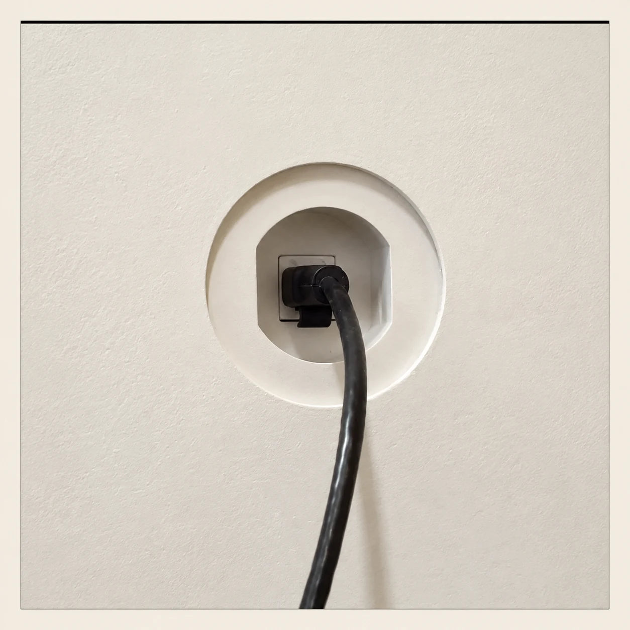 Black network cable connected inside a recessed round wall opening