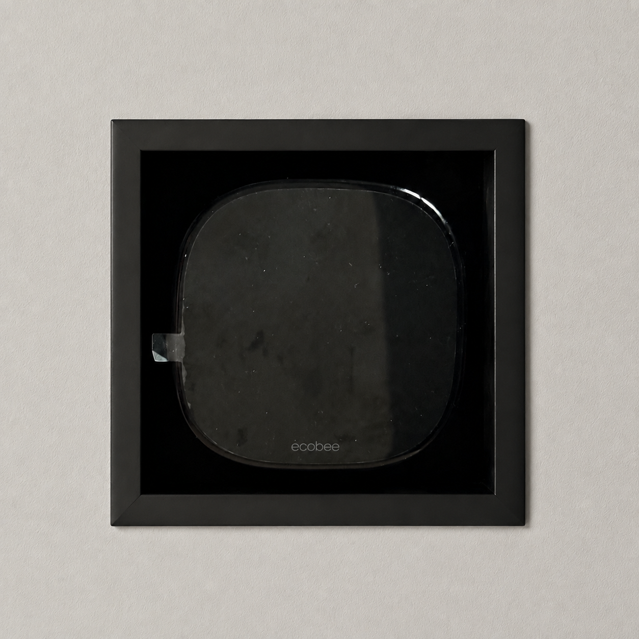 Ecobee Premium thermostat installed in a black recessed drywall mount with a solid visible frame