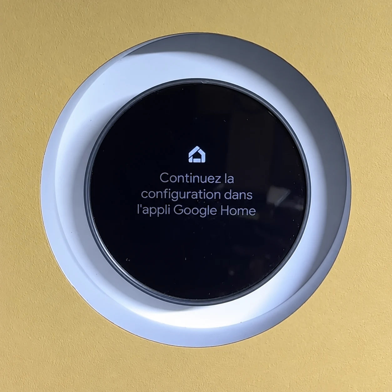 Google Nest thermostat installed in a white trimless recessed mount on a yellow painted wall