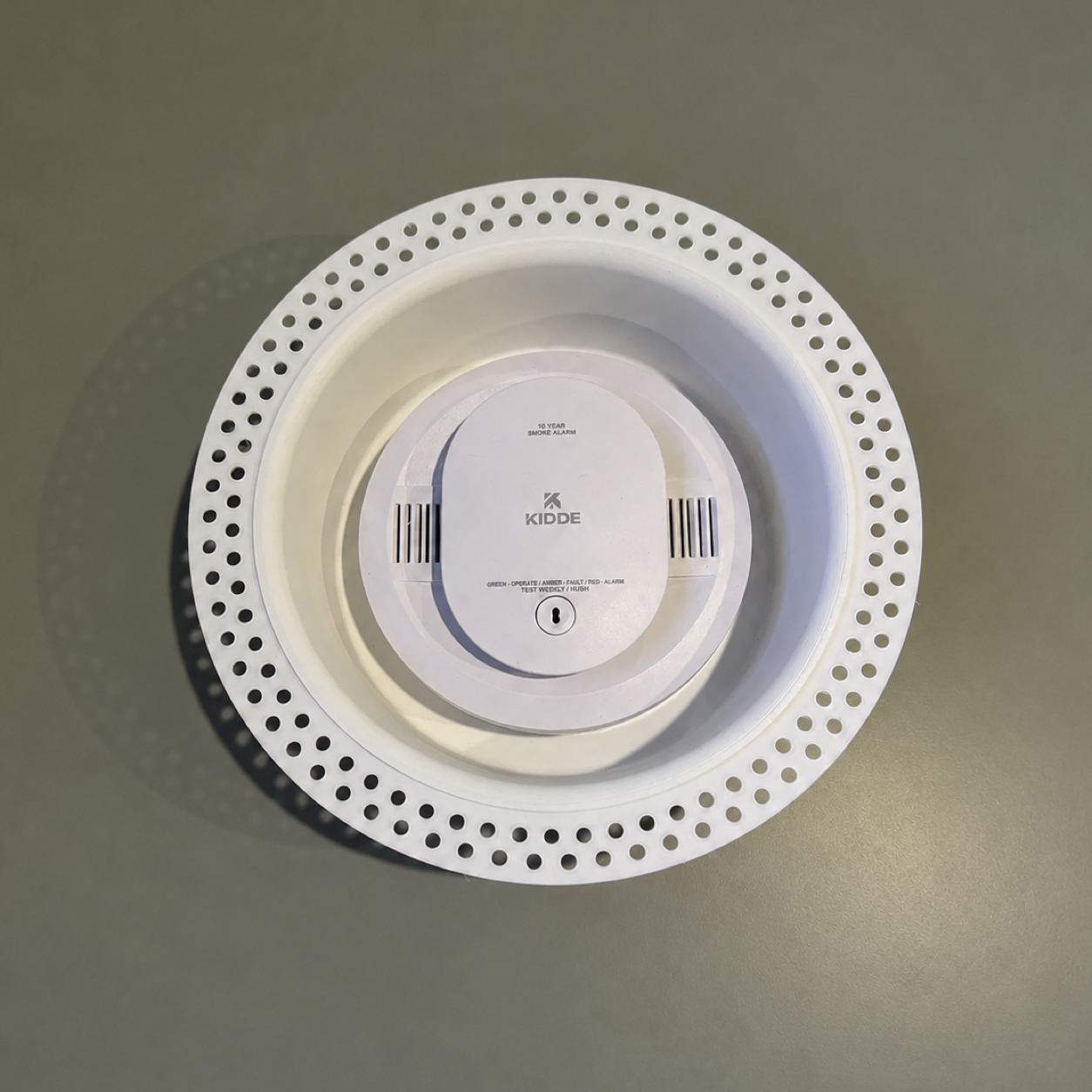 Detector device shown in a white round trimless drywall mount for fit reference; device not included
