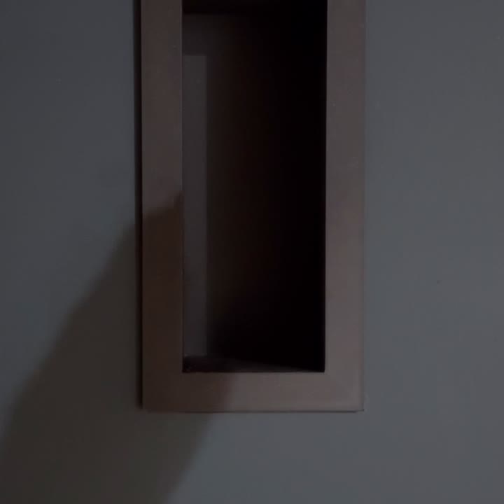 Gloved hands marking, cutting and painting a drywall opening before fitting a black Sonos speaker into a trimless niche